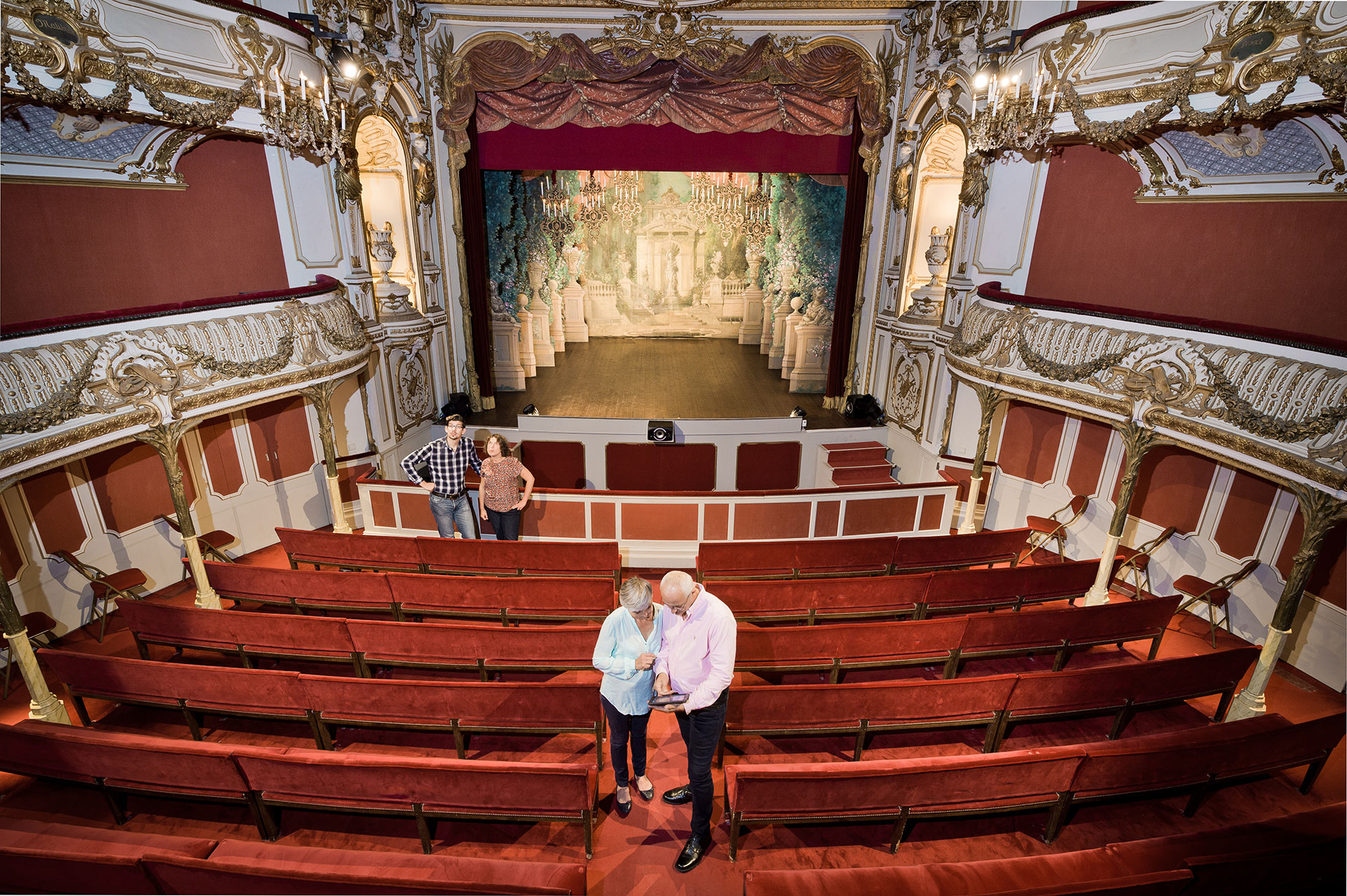 Un couple mature effectue une visite interactive dans la salle du théâtre du Château de Chimay