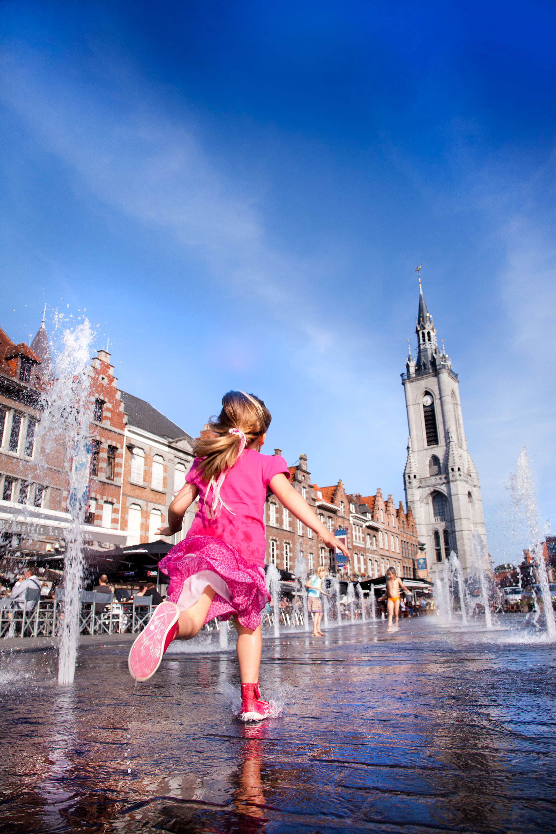 Fille jouant entre les jets d'eau de la Grand-Place de Tournai