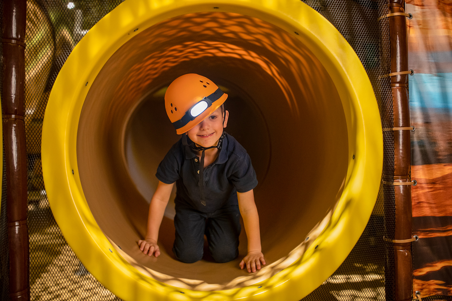 Kind met gele helm in een tunnel in de speeltuin van het vakantiedorp Center Parcs Les Ardennes