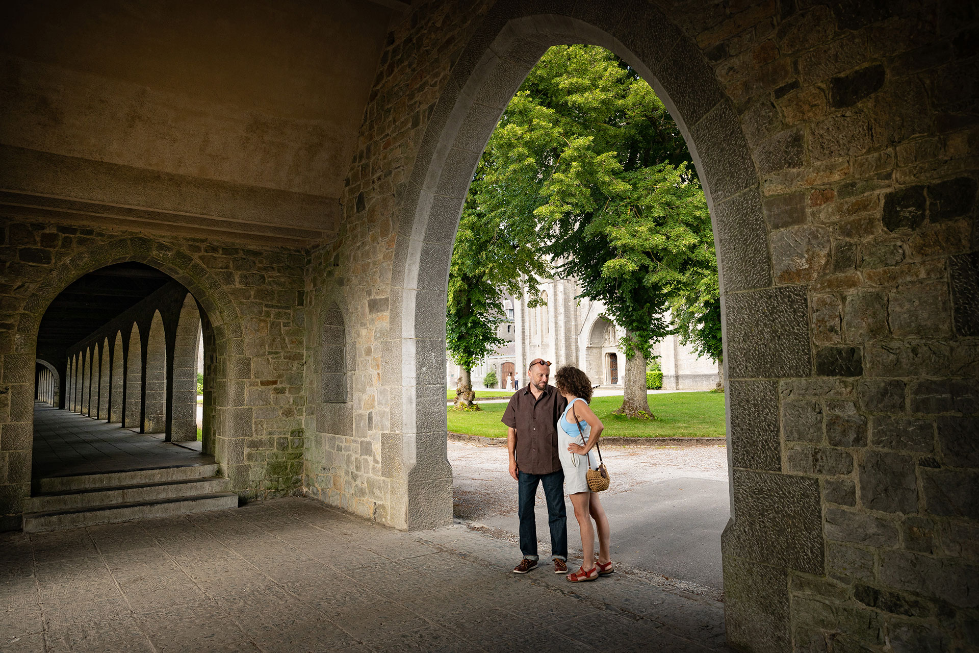 Couple discutant sous les arches de l'Abbaye de Maredsous 