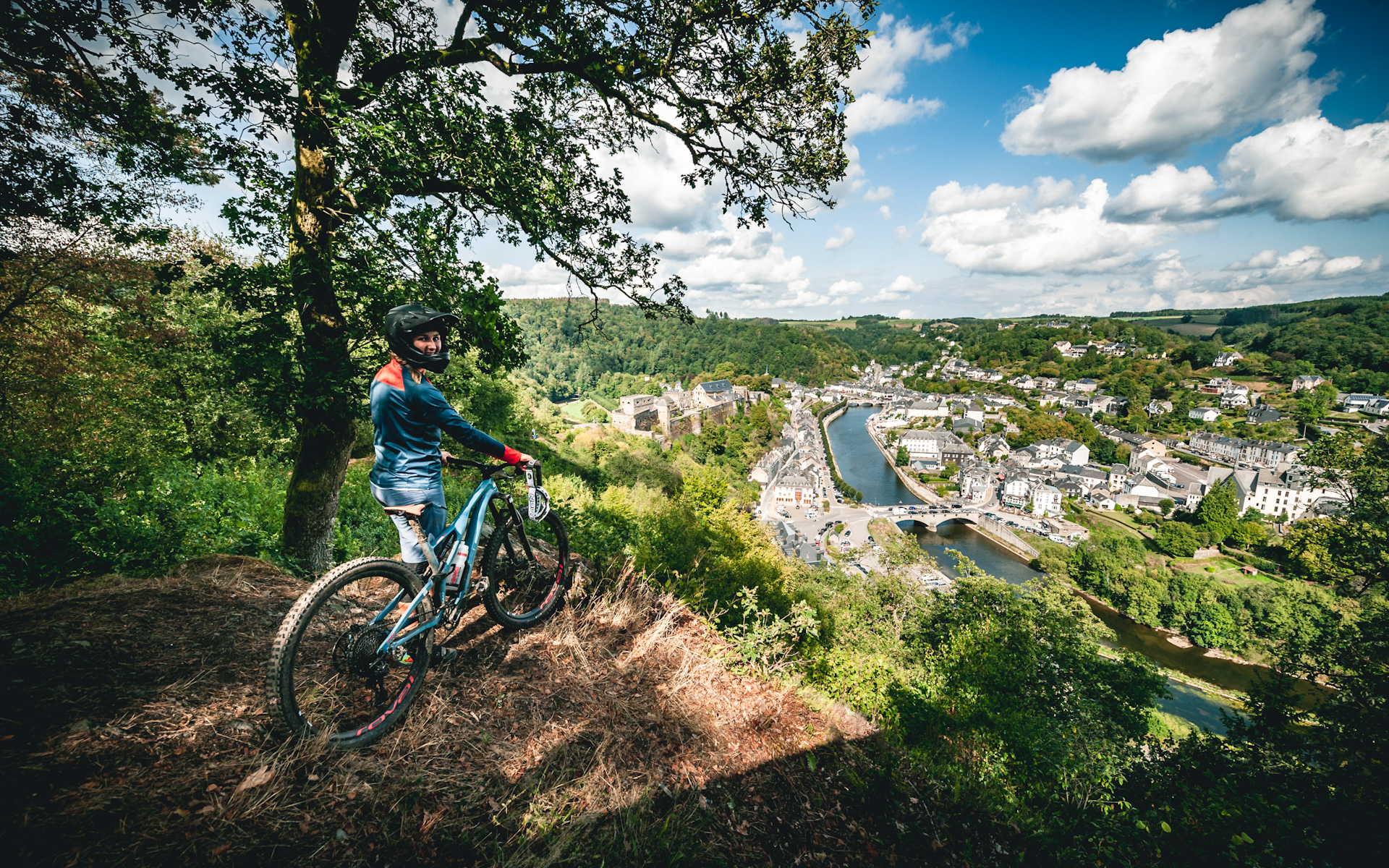 A mountain biker enjoys the view over Bouillon from a trail center path