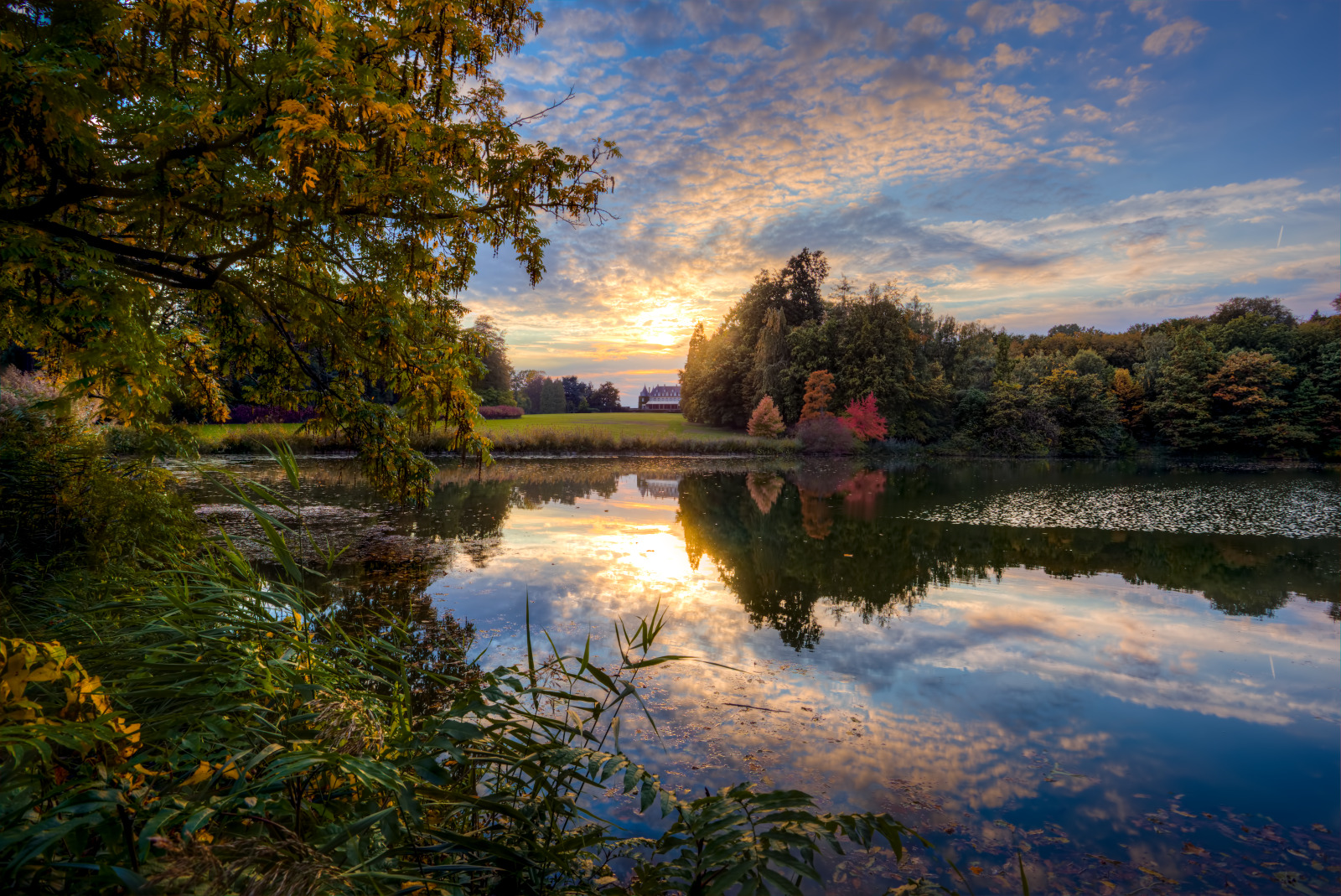Coucher de soleil aux étangs et au parc du Domaine régional Solvay avec le château de La Hulpe situé au fond.