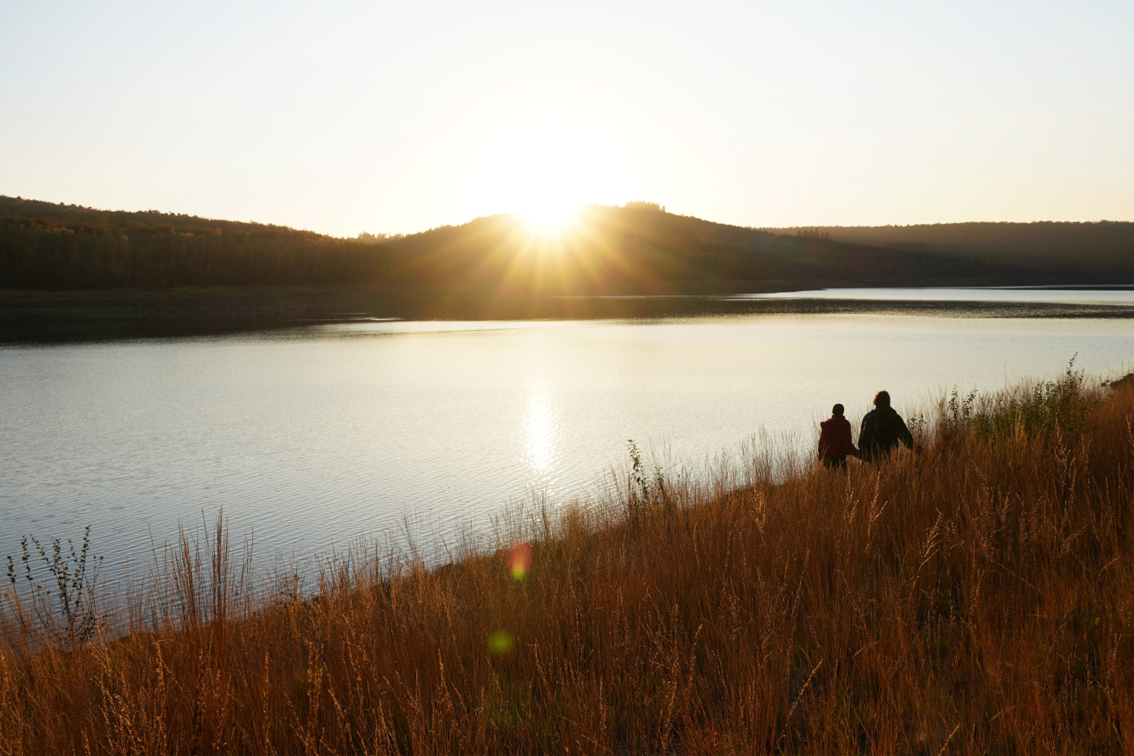 Couple face à un soleil couchant sur un lac