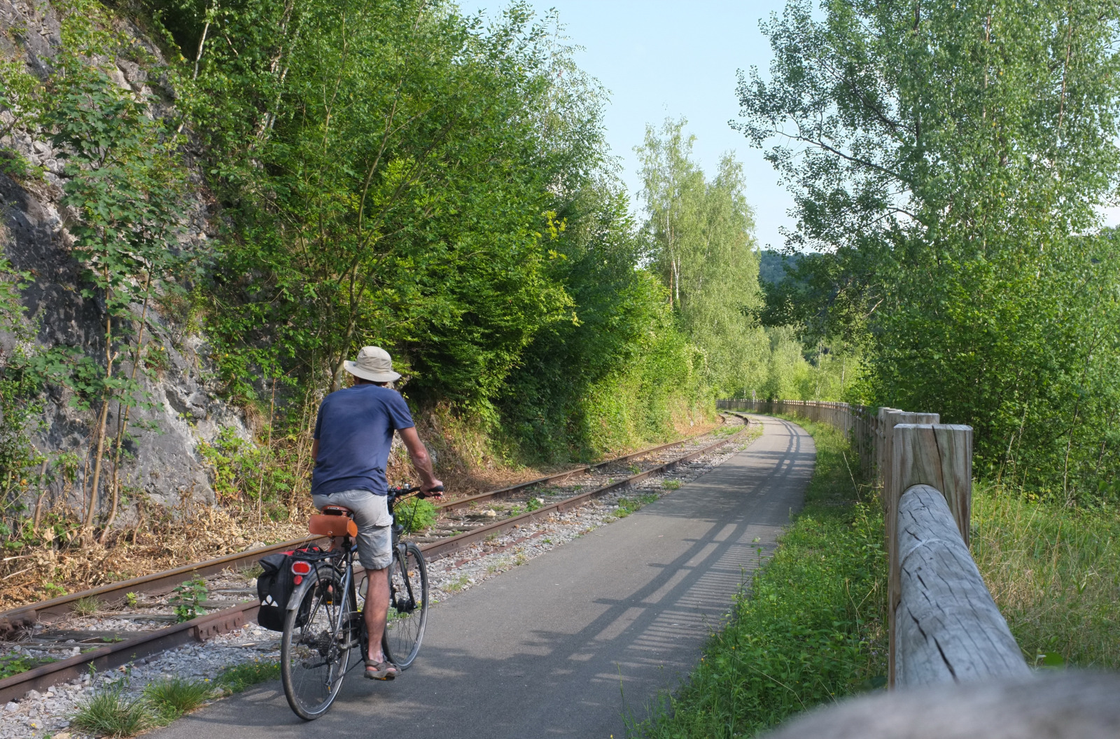 Man, wearing summer clothes, cycling in the Molignée valley