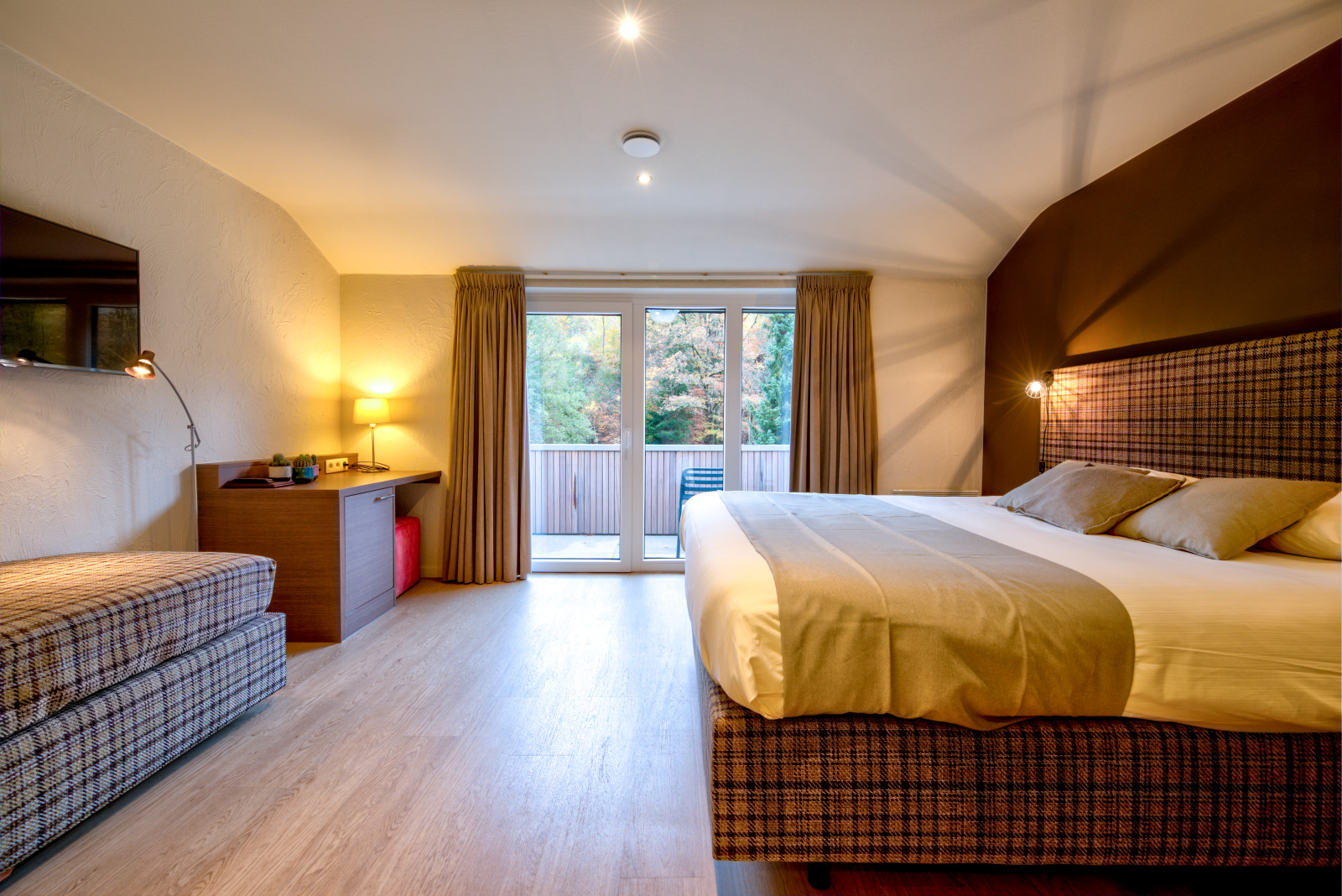 Grand lit, table et porte de la terrasse d'une chambre de l'hôtel Val d'Arimont Resort