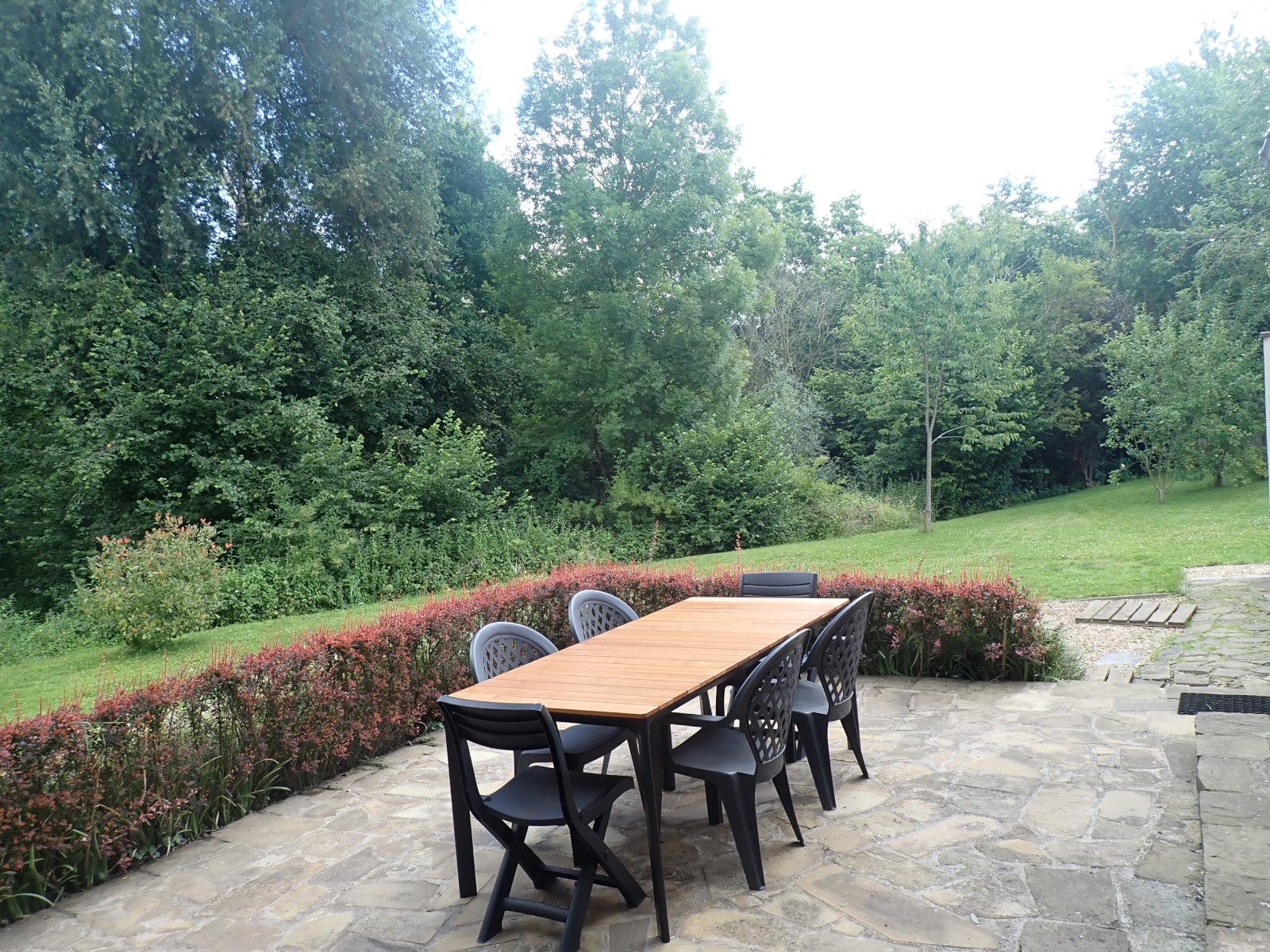 Terrasse avec grande table et des chaises donnant sur le jardin
