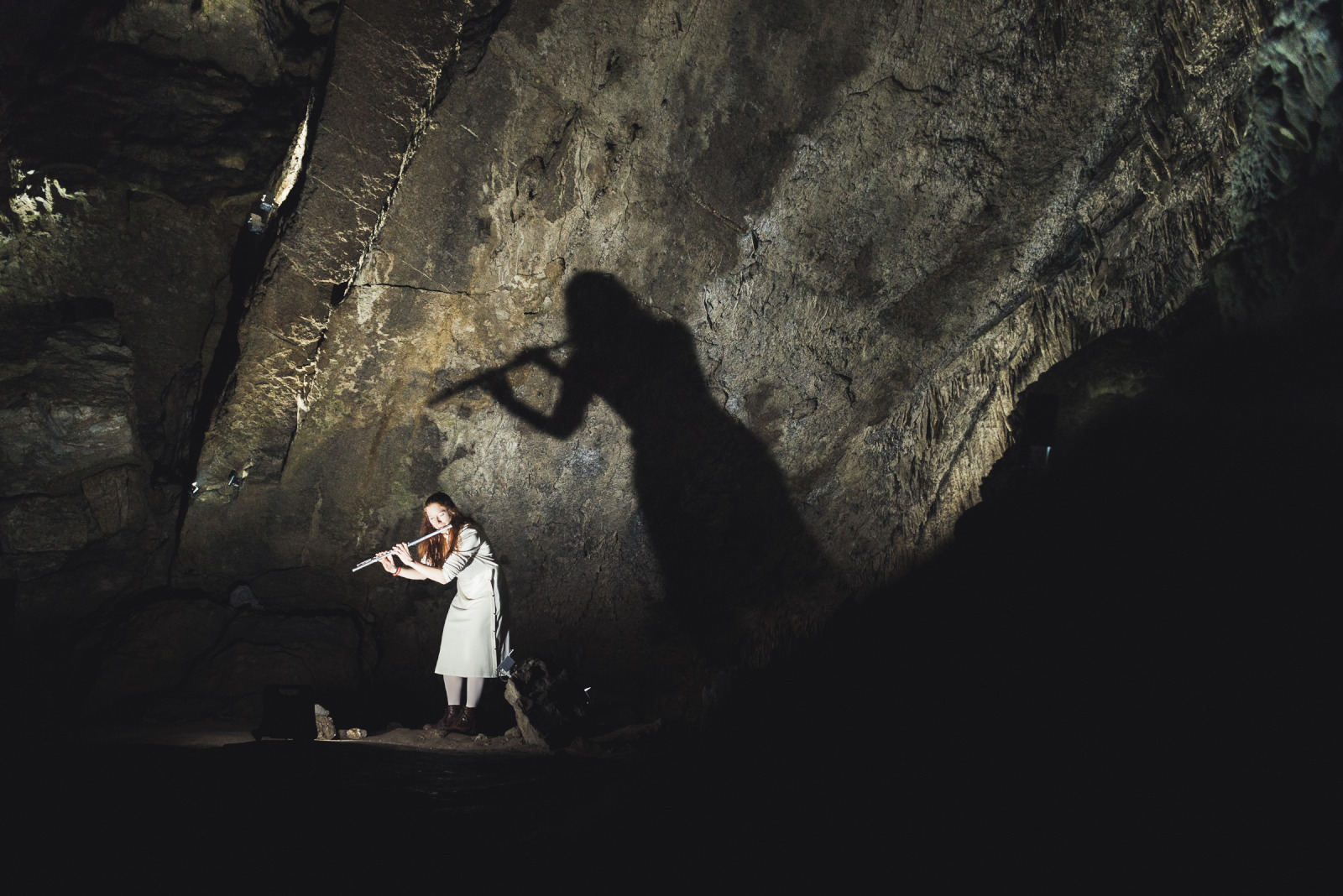 Flutiste jouant de la flûte traversière au coeur des grottes de Han