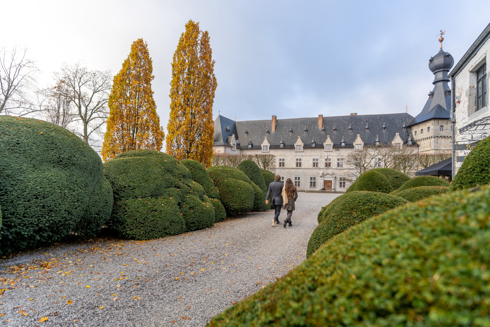 Young couple taking a stroll along the paths of the Château de Chimay gardens