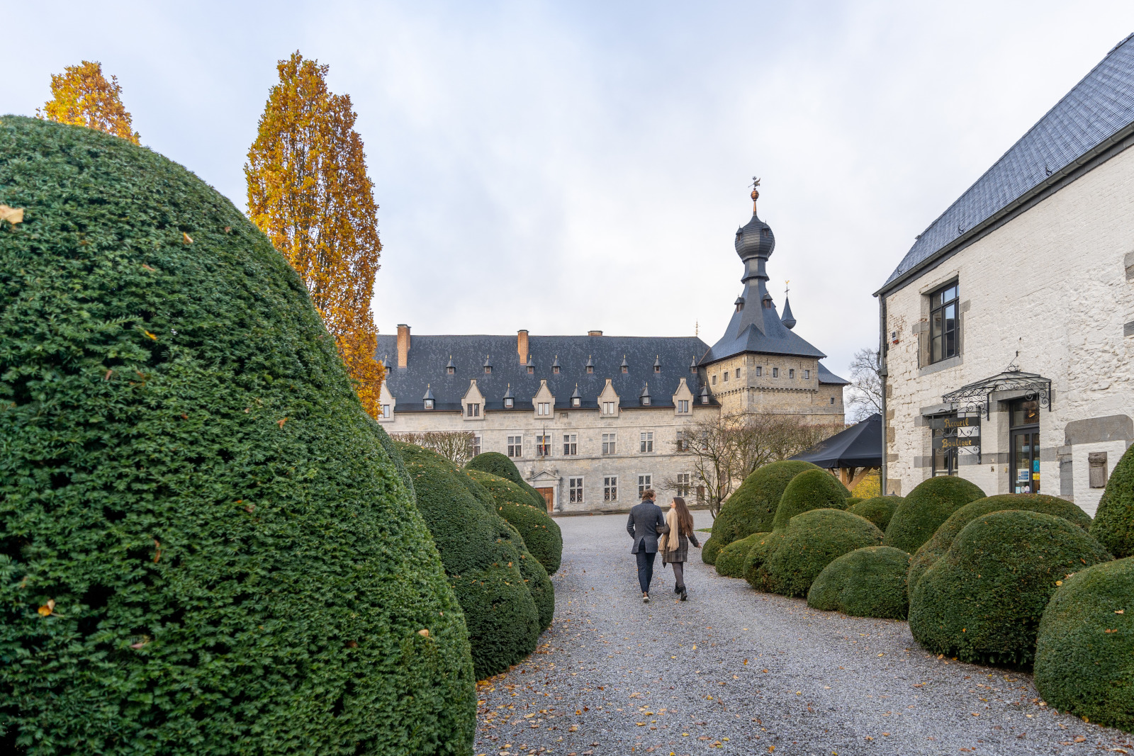 Un couple de jeunes remonte l'allée des jardins du Château de Chimay