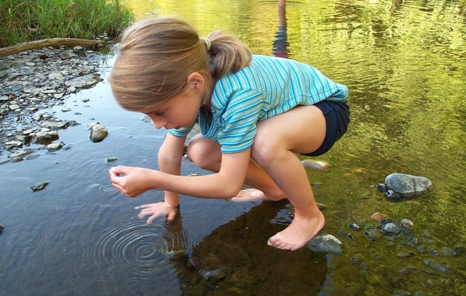 Petite fille jouant au bord d'un point d'eau