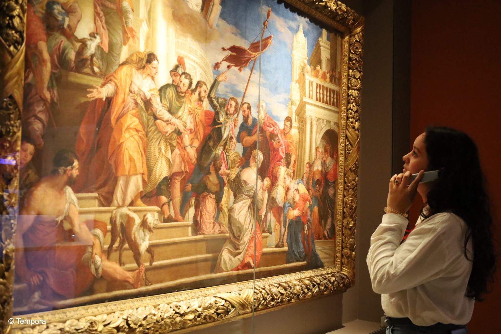 Visiteur devant une peinture du Mudia tenant un audioguide dans la main