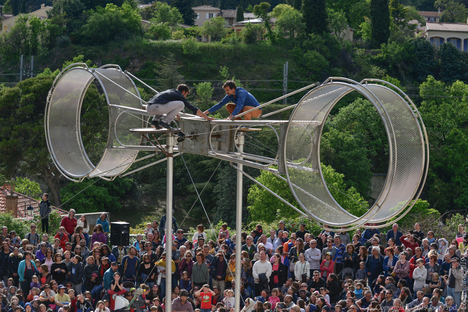 Artistes effectuant des acrobaties dans deux roues métalliques fixées à 10 mètres de sol.