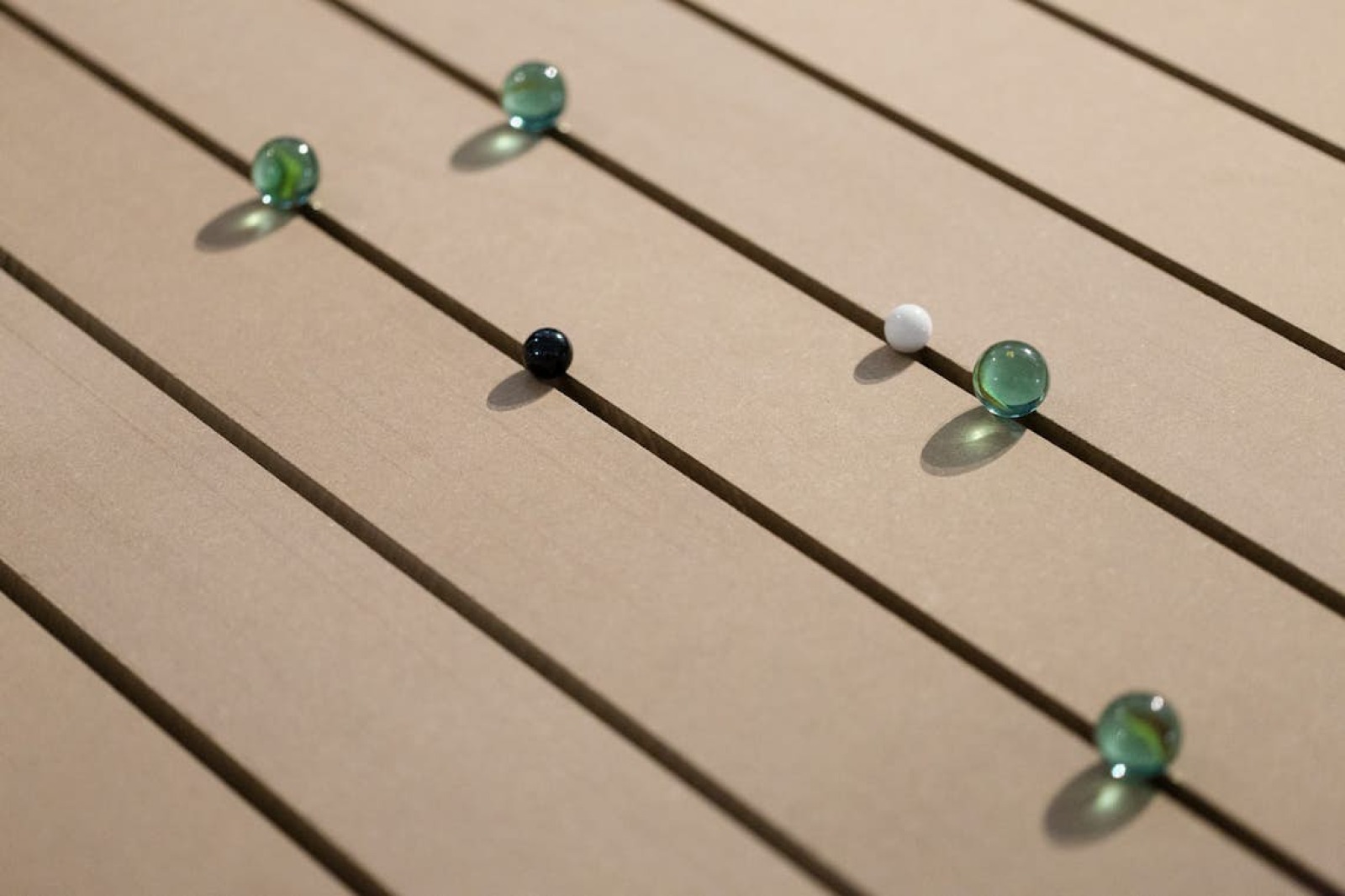 Photo représentant des billes en verre posées sur un sol en bois.