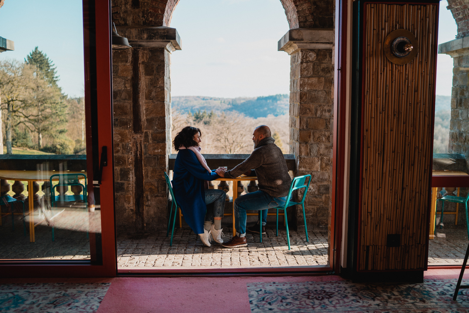 Couple sitting at a table, holding hands at the Domaine de Ronchinne in Assesse