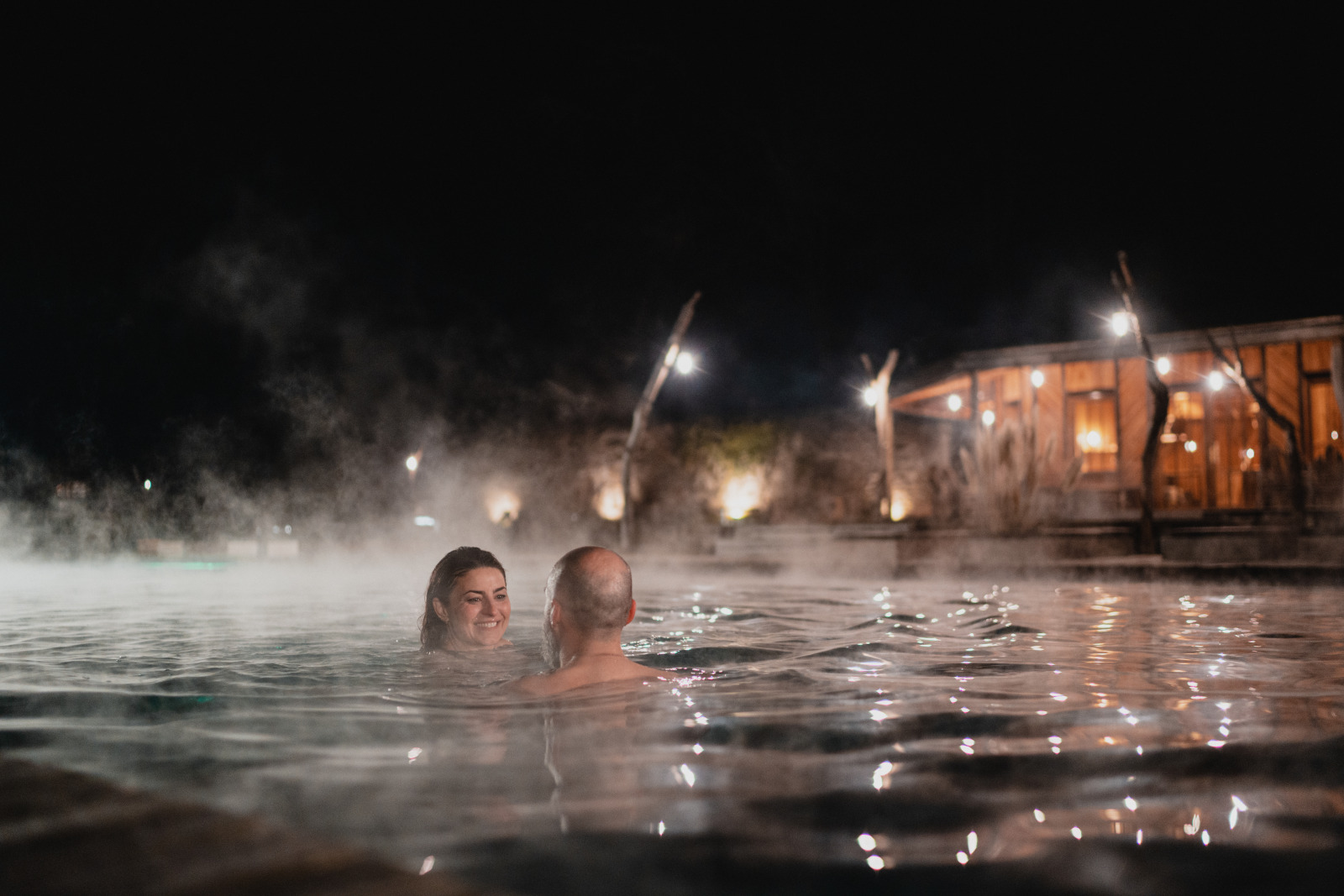 A couple swims one evening in the heated outdoor swimming pool at Domaine de Ronchinne