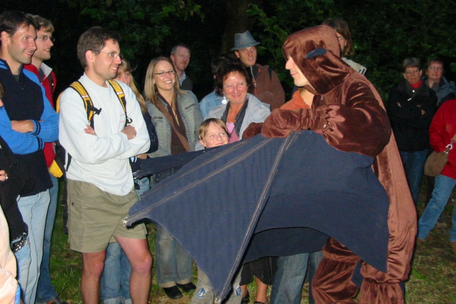 Groupe de visiteurs écoutant un guide nature déguisé en chauve-souris