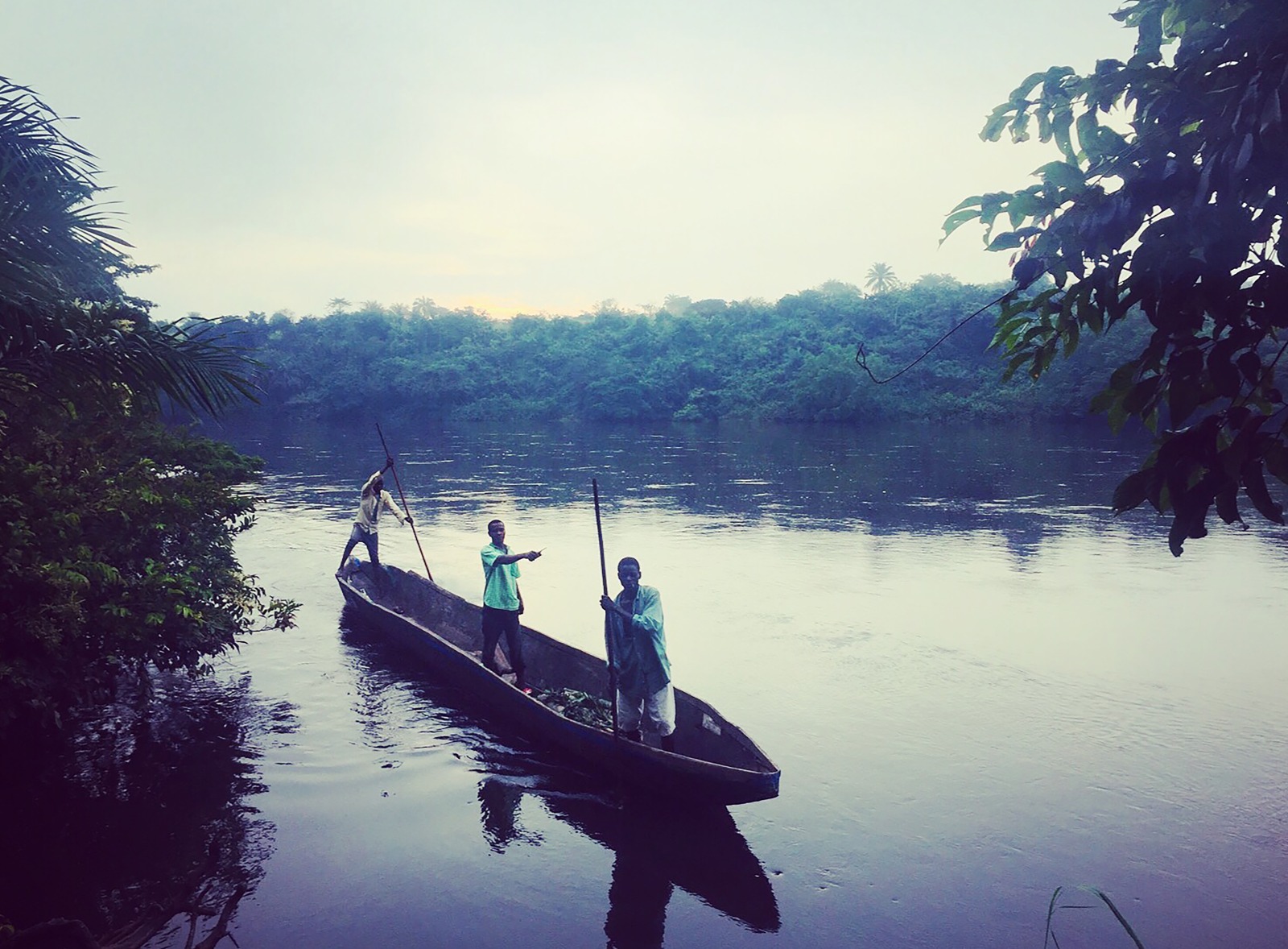 Pirogue sur un lac au Congo avec 3 passagers à son bord.