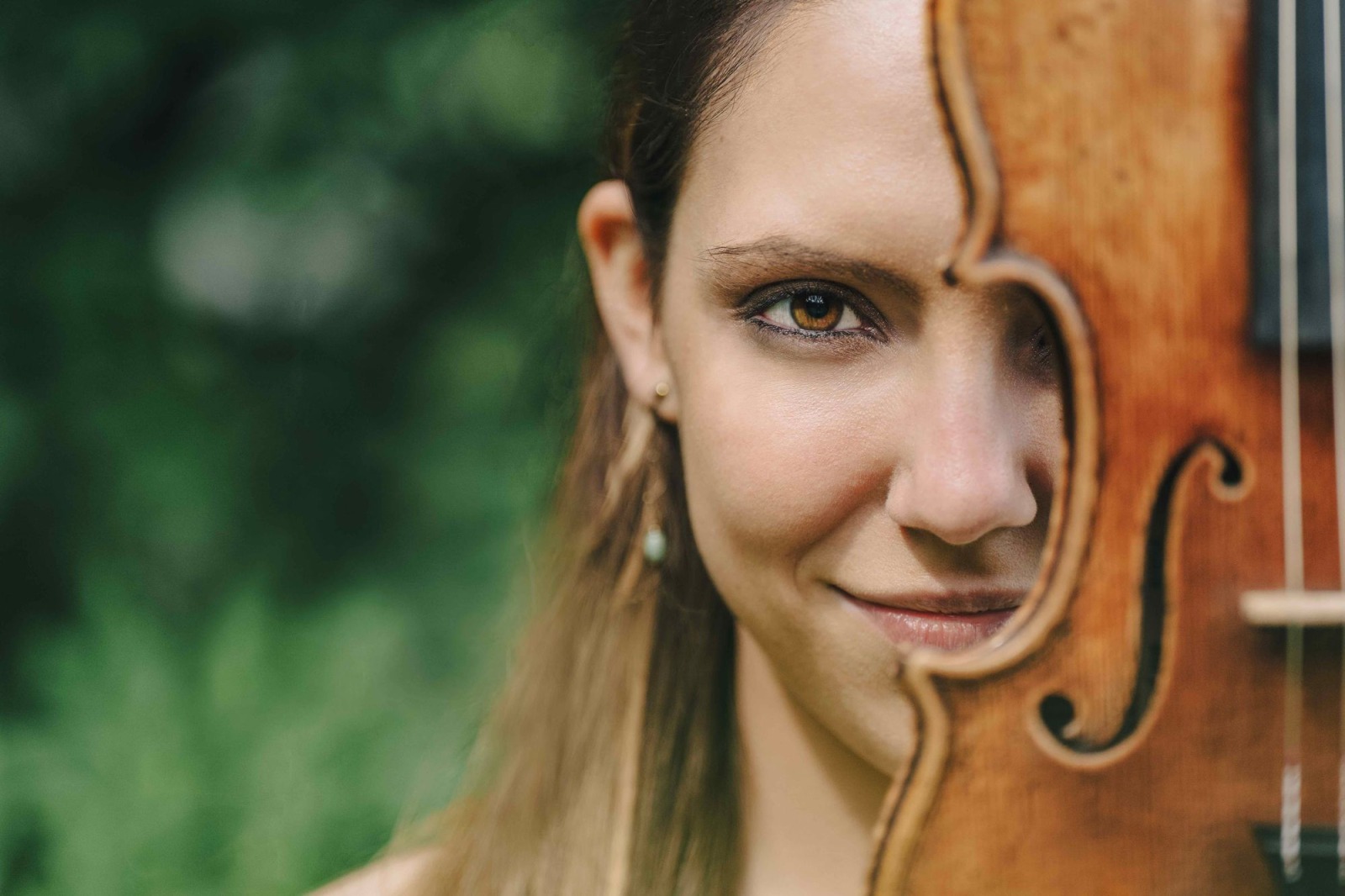 Portret van een muzikante met gezicht deels achter en naast viool