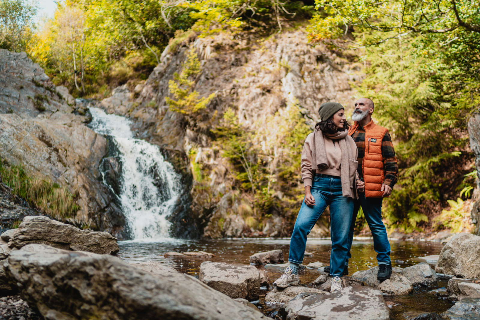 Un couple se tient debout devant la cascade du Bayehon en automne