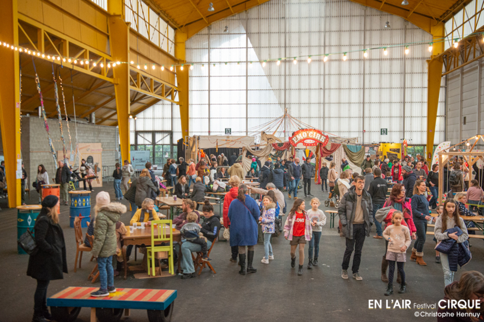 Festival-goers in a hangar where different circus stands are arranged