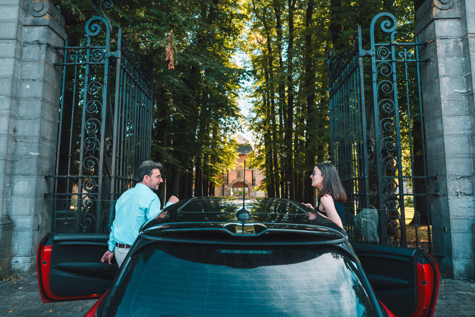 Un couple en voiture devant les grilles d'entrée du château de Bioul