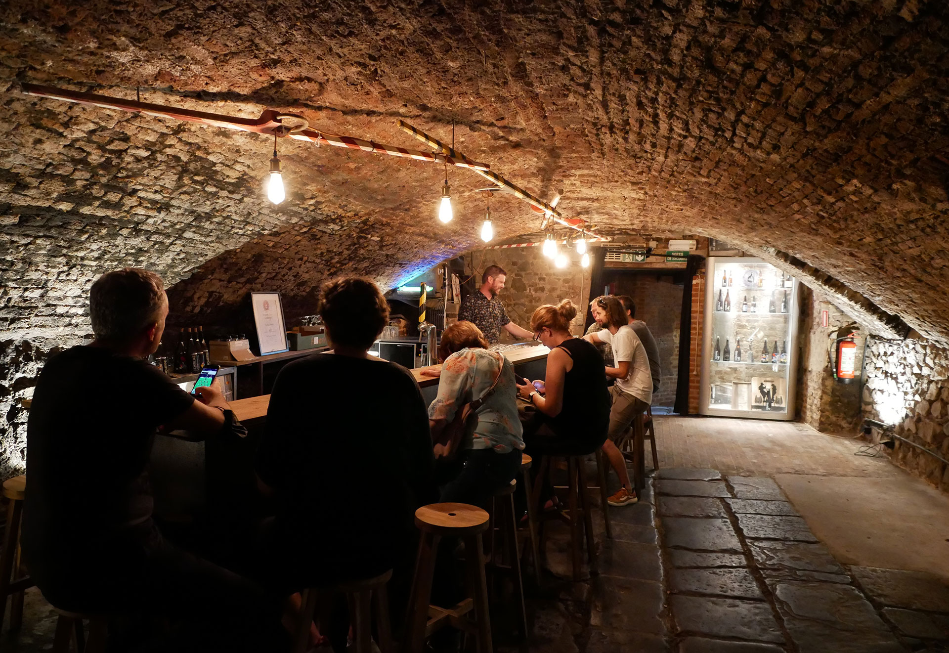 Personnes assises à un bar situé dans une cave voûtée de la brasserie Hoptimalt - Beery - Trip - Namur