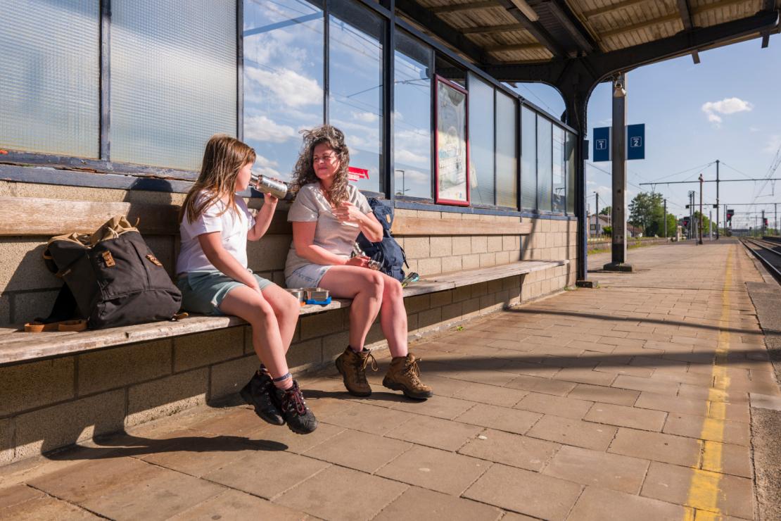 Une mère et sa fille attendent le train sur un quai de la gare de Marloie