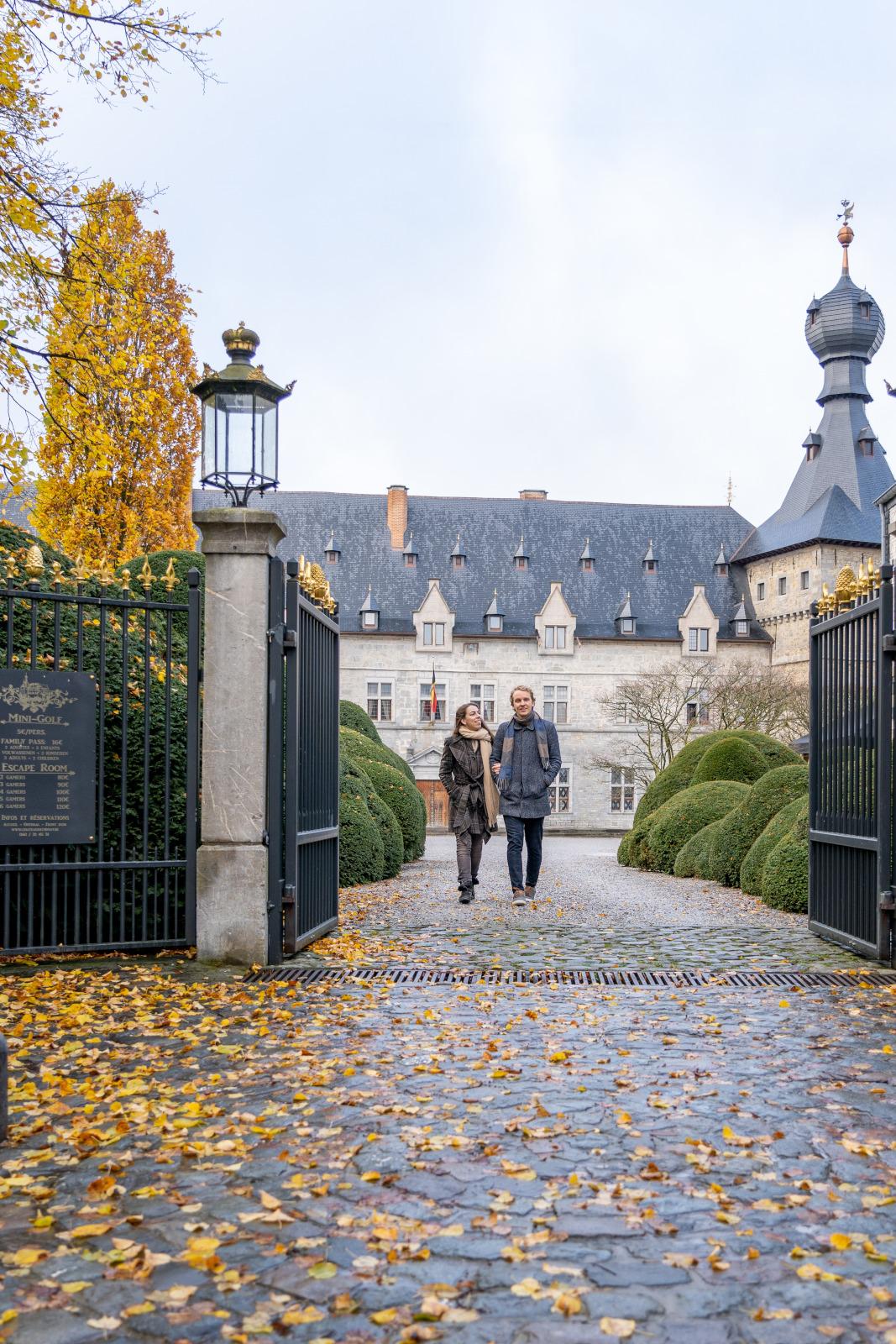 A couple walks by the Chimay castle in autumn