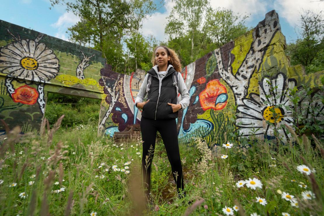 Une femme pose devant une fresque du sentier d'art à Gesves