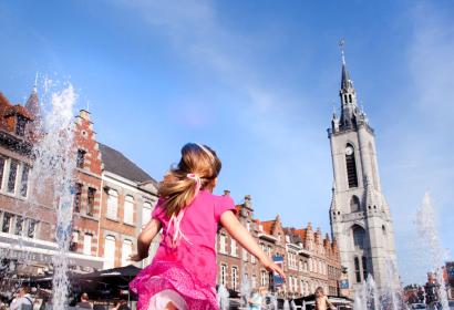 Fille jouant entre les jets d'eau de la Grand-Place de Tournai