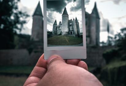 Focus sur une main tenant une photo du château de Vêves, avec le château en arrière-plan 