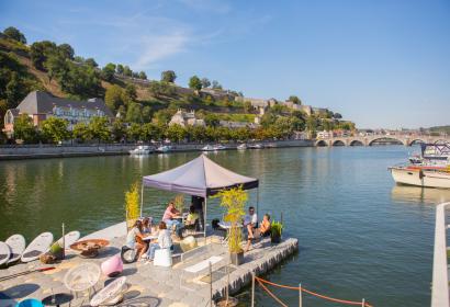 A group of persons settled on a terrace along the Meuse river, at the Capitainerie de Namur