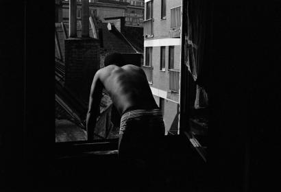 Photo en noir et blanc d'un homme regardant par une fenêtre grande ouverte