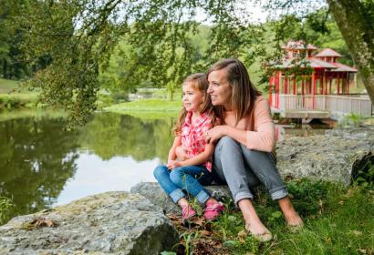 Une petite fille et sa maman profitent d’une pause, assises au bord des étangs du Domaine de Chevetogne