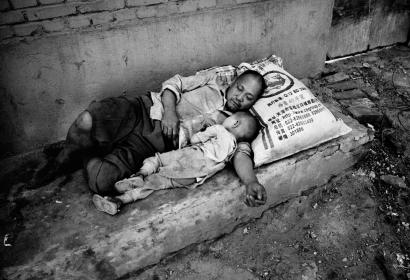 Un homme et son enfant allongés sur un lit de fortune