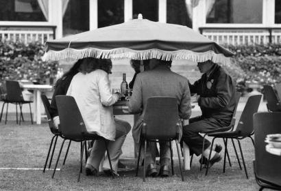 Mensen lunchen in de tuin onder een lage parasol