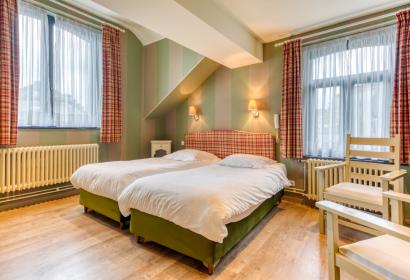 Zimmer mit zwei hübsch dekorierten Betten im Hotel Le Cor de Chasse in Saint-Hubert in Belgien