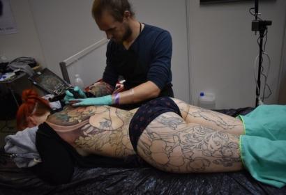 Personne allongée se faisant tatouer sur l'ensemble du corps