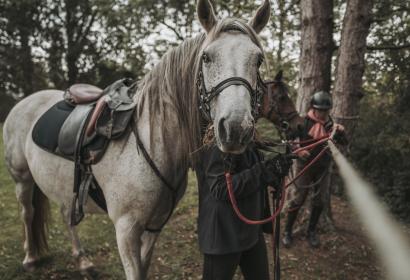 Cavalier qui attache son cheval au cours d'une balade dans le Pays des Lacs