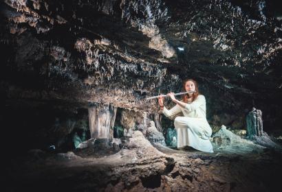 Photo du flutiste jouant de la flûte traversière au coeur de la grotte