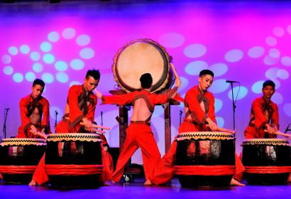 5 musiciens asiatiques jouent du tambour sur une scène