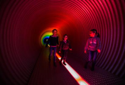 Un groupe de filles traverse un tunnel du parcours de visite de Pass à Frameries