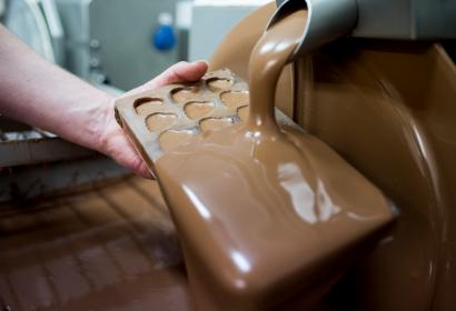 Chocolat pouring over mould at chocolate factory Cyril in Wallonie