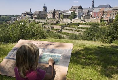 Vor dem Panorama der hängenden Gärten von Thuin liest ein Kind eine Erläuterungstafel