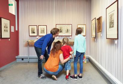 Un couple et ses deux enfants découvrent des œuvres dans une salle d'exposition du Musée Félicien Rops
