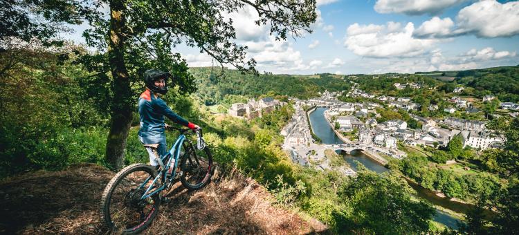 A mountain biker enjoys the view over Bouillon from a trail center path