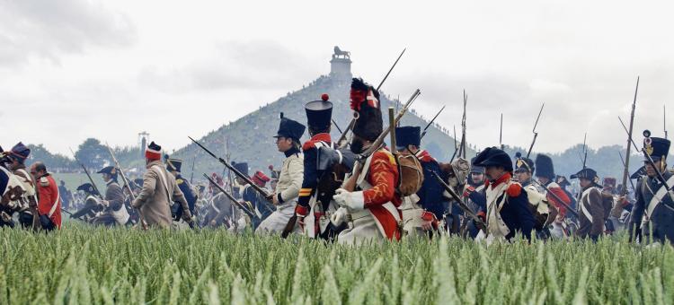 Reconstitution de la Bataille de Waterloo avec des soldats dans les champs et la Butte du Lion en arrière-plan