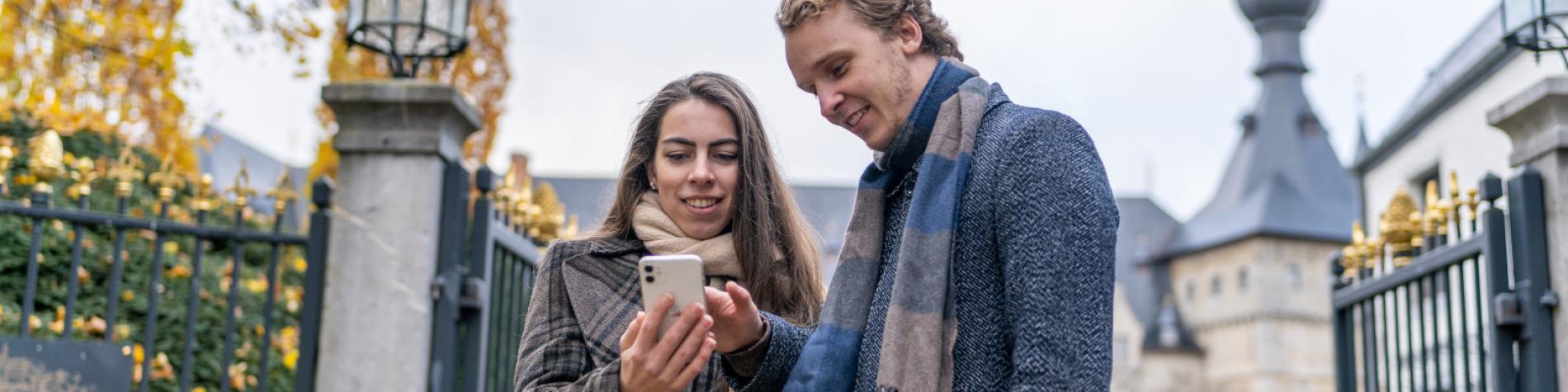 Un couple consulte en automne la web app du Pass sur son smartphone