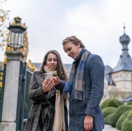 Couple looking at the Pass web app on their smartphone in autumn
