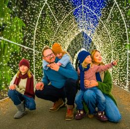 Une famille est accroupie sous un tunnel lumineux à Garden of Lights à Dinant